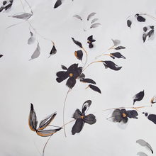 Load image into Gallery viewer, Close-up of black floral print with gold details on white fabric