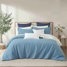 Load image into Gallery viewer, Blue waffle-textured duvet cover set styled on bed with navy and white pillows
